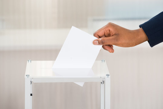 Person's Hand Putting Ballot In Box