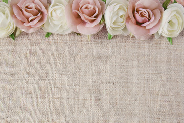 Artificial pink white rose flowers on linen, copy space backgroud