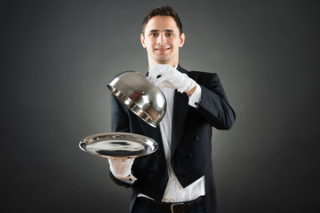 Portrait Of Waiter Holding Cloche Over Empty Tray