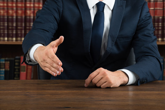 Lawyer Offering Handshake At Desk In Courtroom