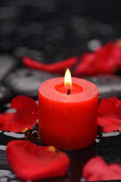 Red rose petals with candle and therapy stones 
