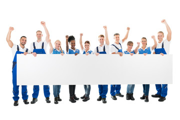 Obraz premium Happy Janitors With Arms Raised Holding Blank Billboard