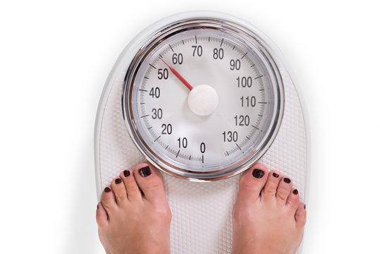 Woman's Legs On Weighing Scale Over White Background