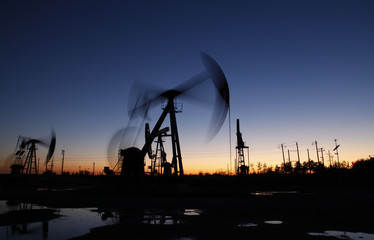 Fototapeta na wymiar Oil field scene, the evening of beam pumping unit in silhouette