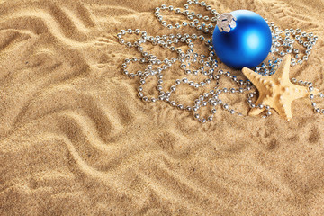 Christmas ball with beads and starfish on a yellow sand