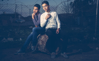 Two boys sitting on barrel in darkness in Iraqi countryside