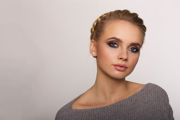 portrait of a beautiful young blonde woman on a light background with hairdo on her head. copy space.