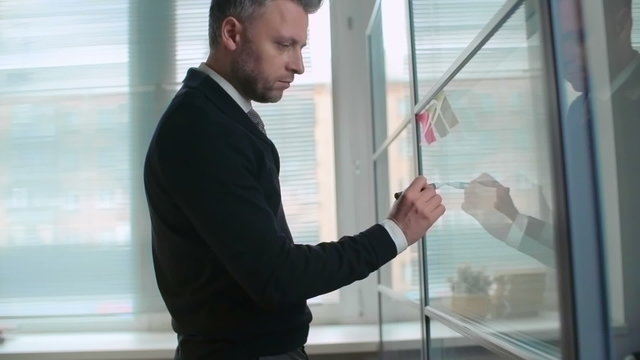 Businessman planning his profit growth and drawing it on a glass wall
