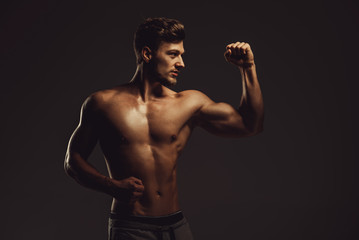 Obraz na płótnie Canvas Athletic handsome man showing biceps muscles