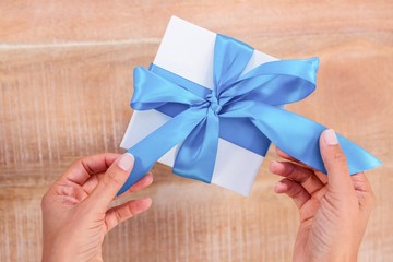 Woman presenting gift with blue ribbon
