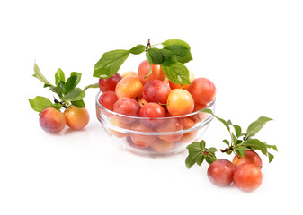 fresh plums in a glass container on a white background