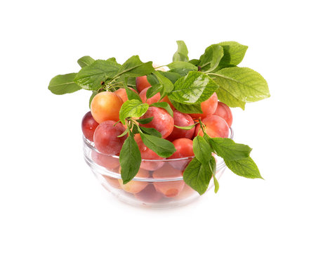 fresh plums in a glass container on a white background