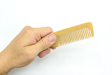 Hand holding wooden comb on background