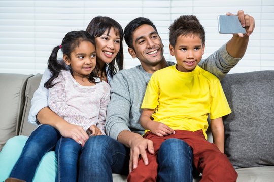 Happy family taking selfie on sofa