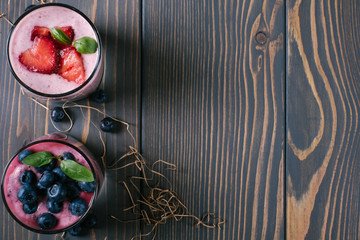 Smoothie with blueberries and strawberries in a glass on a wooden background with a free space top view