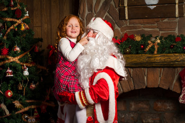 Santa Claus holds on hands happy little girl.