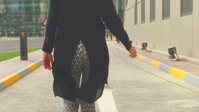 Woman running down the street - tilt from the feet to the building - slow motion