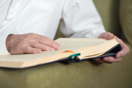 An old man hands reading Koran. Selective focus