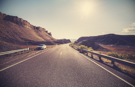 Retro toned desert highway against sun, travel concept