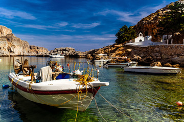 Greece, island Rhodes. View of a bay with boats and an church in