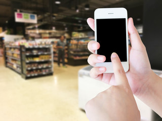 Hand holding mobile phone with blank screen with blur supermarke