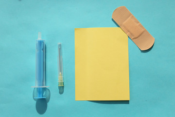 Syringe, needle and plaster on blue background and copy space - medicine concept