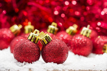 Red Christmas balls on snow against red bokeh background