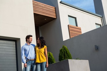 Happy couple standing in front of new house