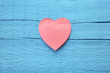 Fototapeta premium Blank pink paper note with heart shape on grunge blue wooden background with copy space