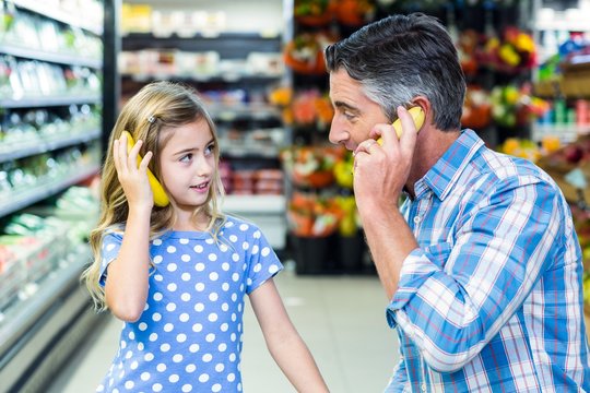 Father and daughter playing with bananas - Powered by Adobe