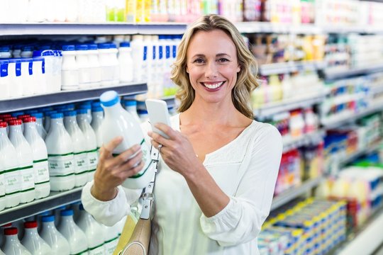 Beautiful woman taking a picture of milk bottle