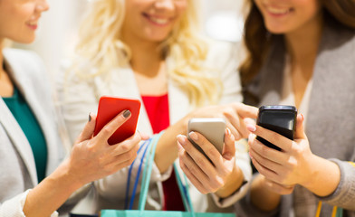 happy women with smartphones and shopping bags