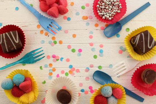 Birthday celebration cupcake, candy, plastic fork and spoon and confetti background 
