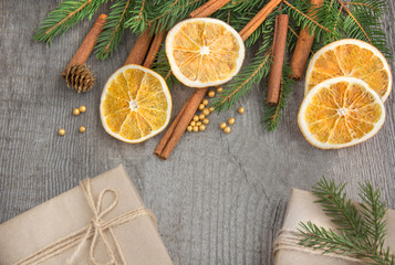 Fototapeta na wymiar Traditional Christmas frame with spices, decorated with dried orange around central copyspace on a rustic wood background for your Christmas message.