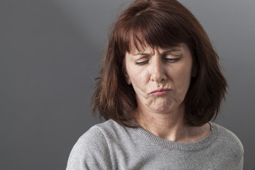 judge mental concept - unhappy 50s woman expressing disagreement and doubt with pouting face,studio shot