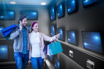 Smiling couple walking hand in hand looking televisions 