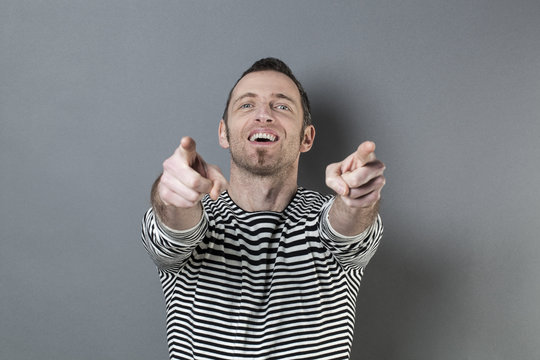 body language concept - fun 40s man enjoying pointing to a product or advertisement in front of him with focused hand gesture,studio shot on gray background