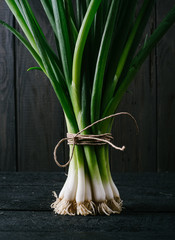 Scallions on a black wooden background close-up with a free space