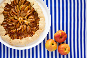 Open pie or galette with apples on striped background