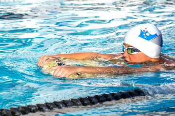 Boy exercising flutter kick with board.