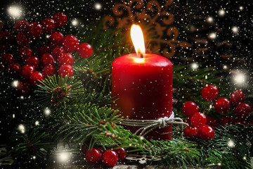 Christmas or New Year's dark composition with burning red candle