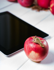 Tablet with apples on a white wooden background