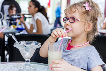 Little girl is drinking lemonade at restaurant.