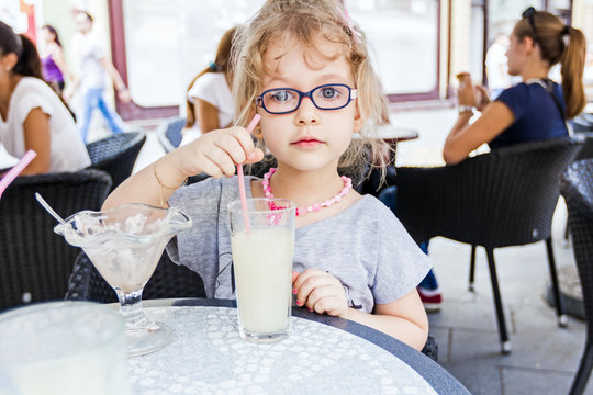 Little girl is drinking lemonade at restaurant.