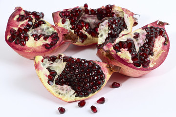 Pomegranate broken and seeds over white
