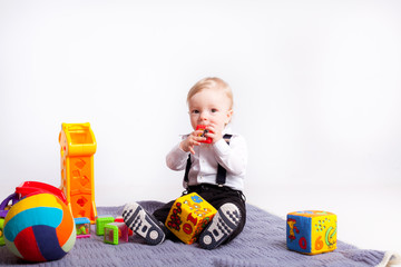 Little boy play with toys on blanket over white background