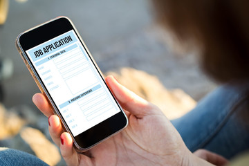 woman sitting in the street holding her smartphone with job appl