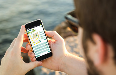 Man using his  mobile phone on the coast with car sharing app on