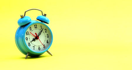 blue alarm clock on a yellow background, time concept
