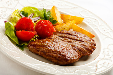 Grilled steak, baked potatoes and vegetable salad 